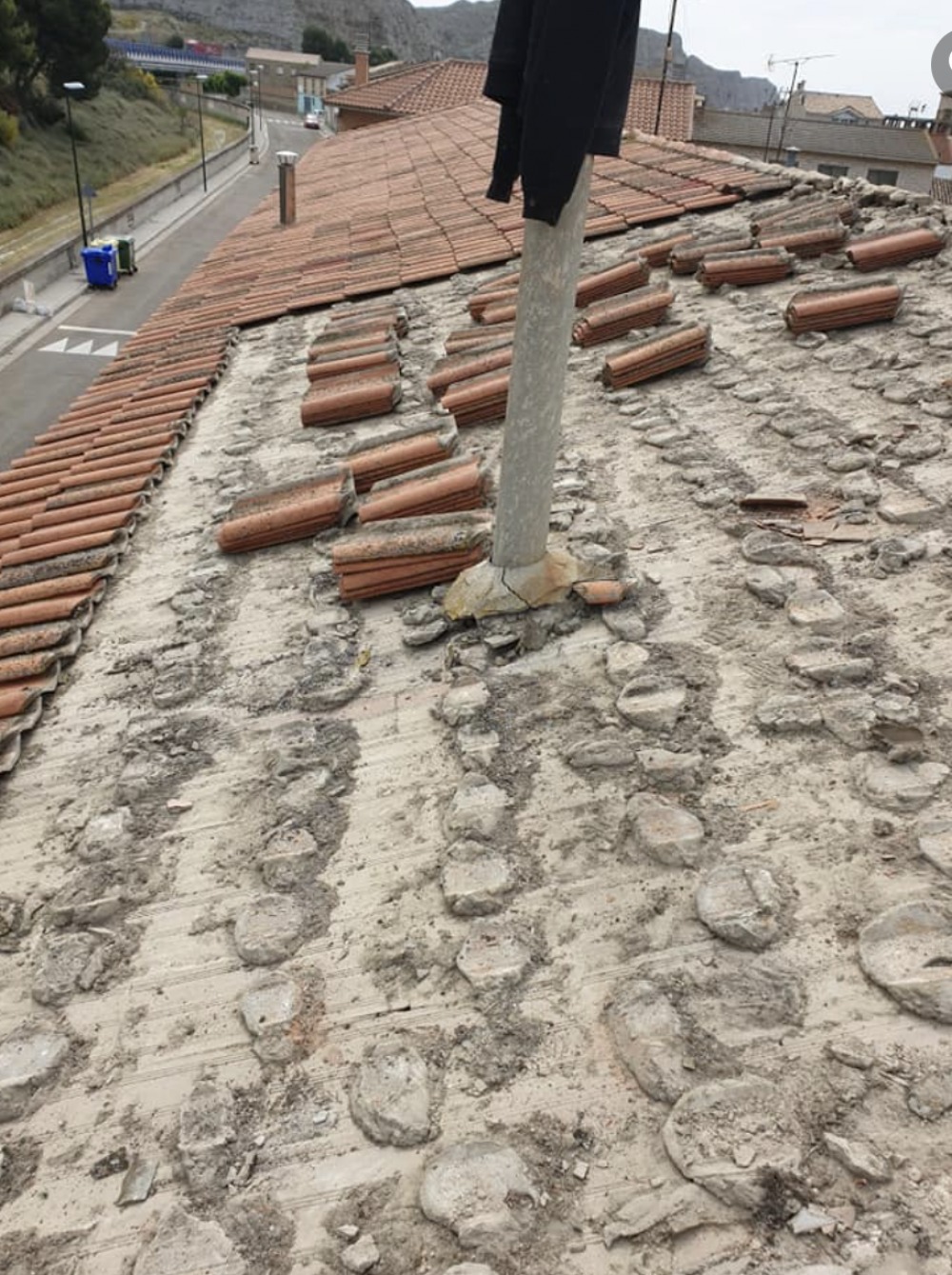 Detalle de un profesional de TEJADOS MORAL reparando grietas y daños en una fachada antigua, usando materiales premium